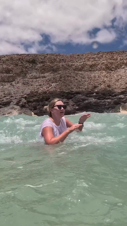 Menina molhando jeans no oceano e nadando em camiseta branca molhada