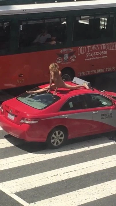 Woman dancing on a car in a busy street