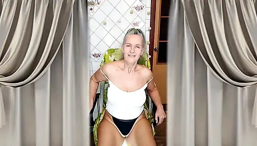 Cheerful housewife Lukerya flirts in the kitchen in tight denim shorts.