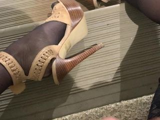 Siyah şeffaf çoraplar ve halka açık merdivenlerde kayış topuklu ayakkabılar