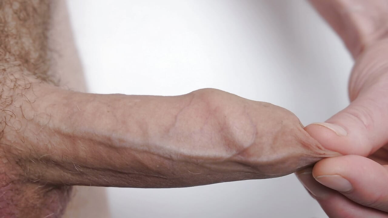 Very Close up foreskin and bell-end a man plays with the gland of his erect uncut cock