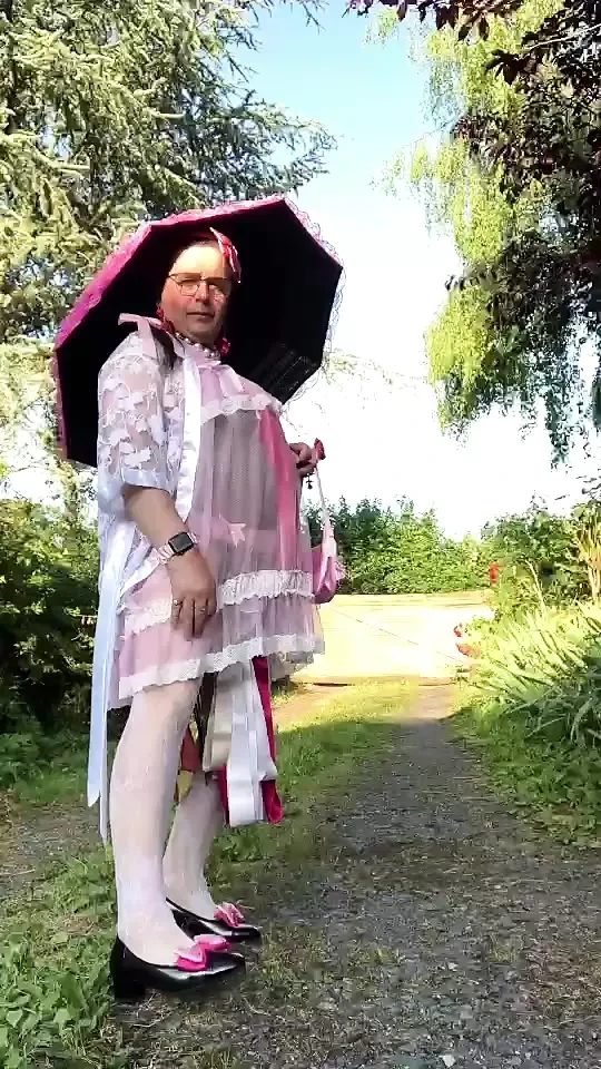 In an outfit with a pink nightgown and a sheer white dressing gown with a parasol