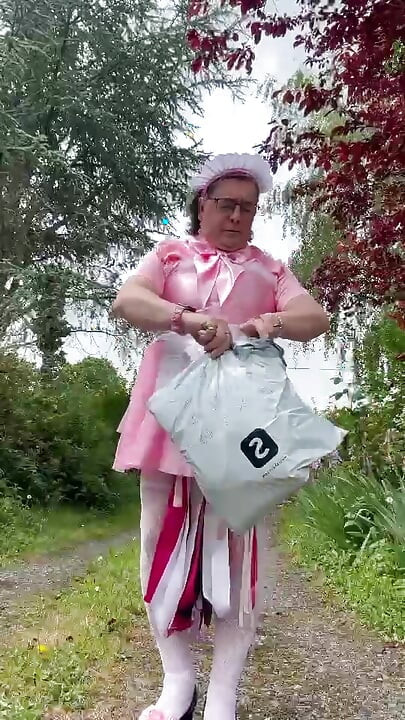 Vestida com uma roupa de empregada rosa para pegar um pacote na caixa de correio