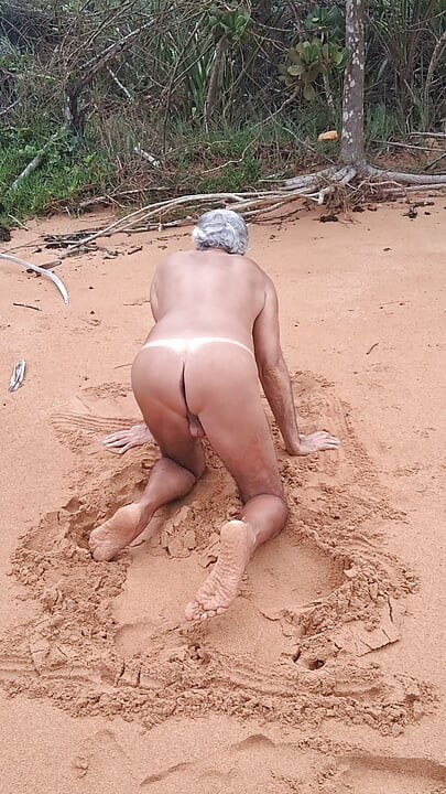 Ladysilva på stranden naken och visar upp sin solbrända heta rumpa