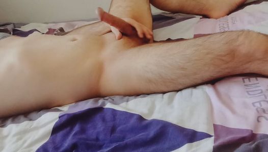 A guy is jerking off alone at home on the bed and cumming