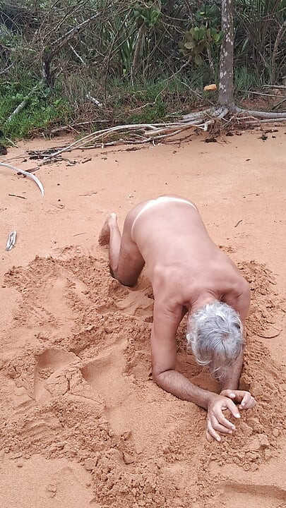 Ladysilva på stranden naken og viser frem sin solbrune, varme rumpe
