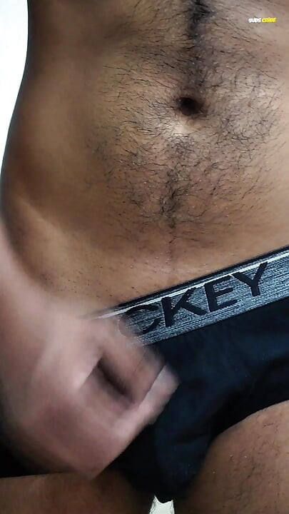 Young man wearing black underwear is dancing cock while holding his groin area.