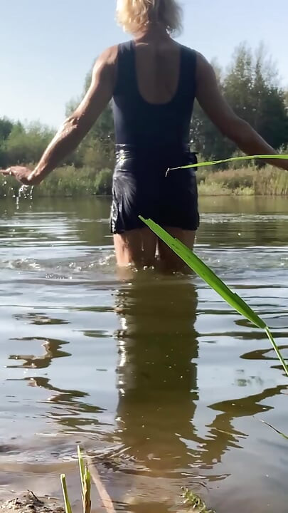 Trans djevojka pliva u jezeru u plavoj sportskoj haljini. Wetllok trans djevojka mokra.