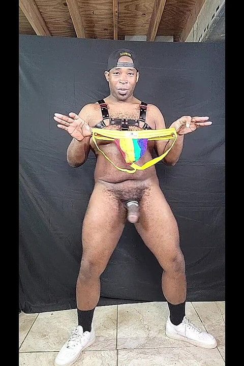 Dekhengst met grote lul die enorme pik aftrekt in een regenboogprint-jock