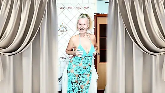 A mature blonde in a knitted dress shows off her curves in a home environment.