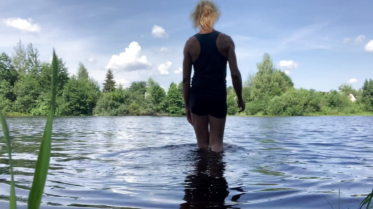 Trans djevojka Alexa Cosmic pliva i igra se u jezeru u crnoj kratkoj i plavoj majici