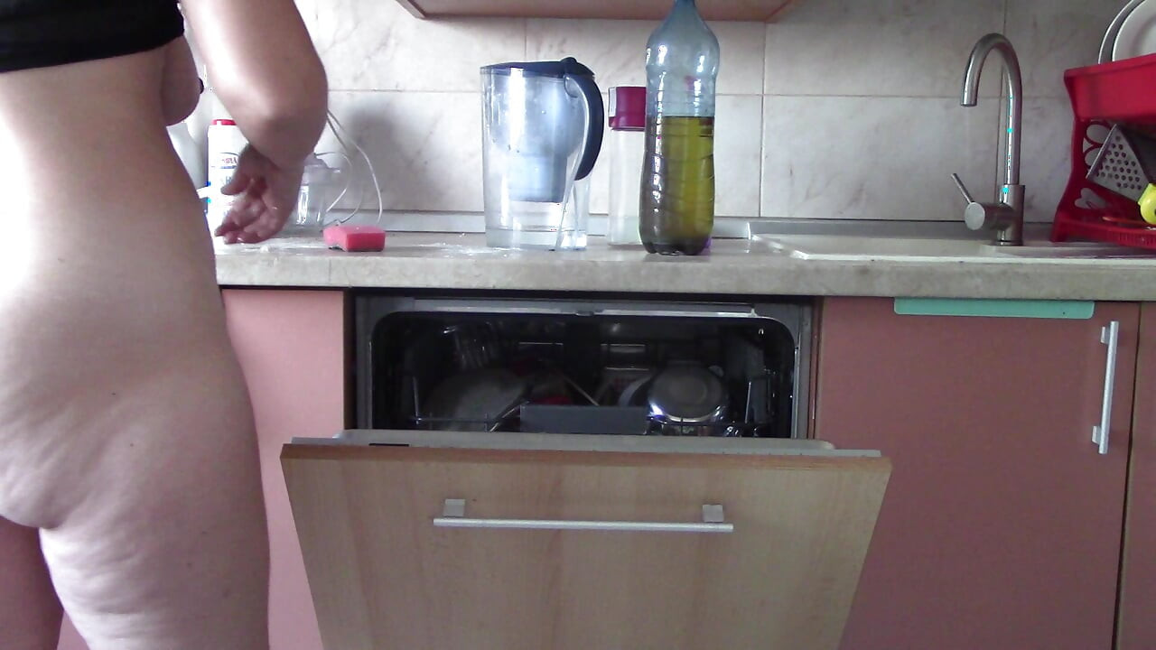 Sexy naked woman preparing food in the kitchen. Hairy brown hair, big ass, big.