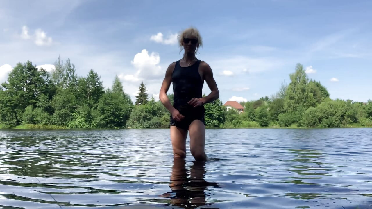 Trans djevojka Alexa Cosmic pliva i igra se u jezeru u crnoj kratkoj i plavoj majici