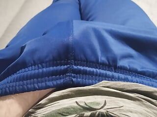 Facet w niebieskich spodniach dresowych pociera wybrzuszenie
