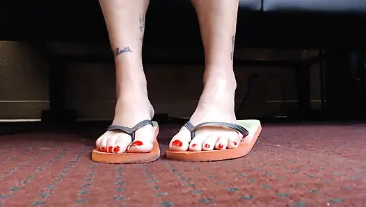 Игра с шлепантом обуви с красными ногтями крупным планом