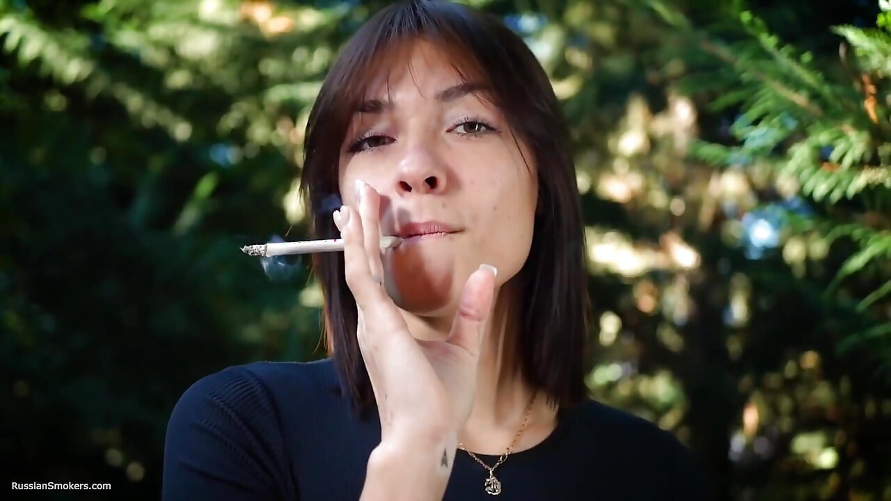 Doce beleza russa fumando cigarro na natureza
