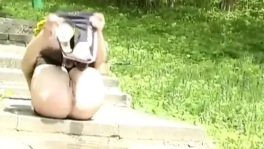 Young beautiful Woman pissing on the Stairs in the Park.