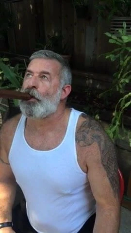 Viejo barbudo fumando puro