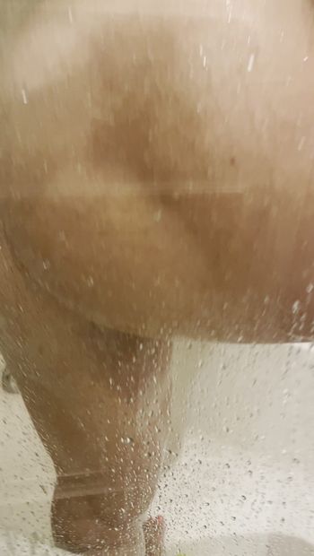 Des seins mouillés dans une fenêtre sous la douche en sueur