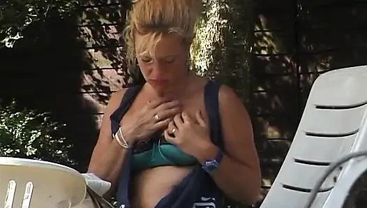 Sarışın orta yaşlı seksi kadın açık havada göğüslerini gösteriyor