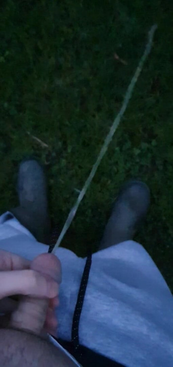 Kencing di luar ruangan dengan sepatu bot karet celana olahraga abu-abu