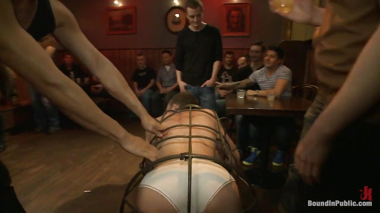 Stud in a metal cage is fucked by horny bar patrons