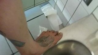 Pieds nus dans des toilettes publiques sales et tapotant de la pisse