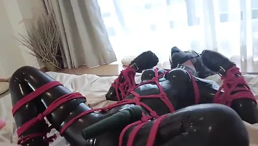 Lateks takım elbise giyiyor ve kırmızı iple bağlı