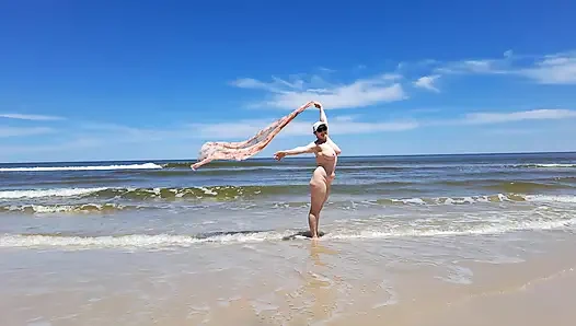 Rekaman seks amatir. Seorang nudis bermain dengan ombak di pantai laut.