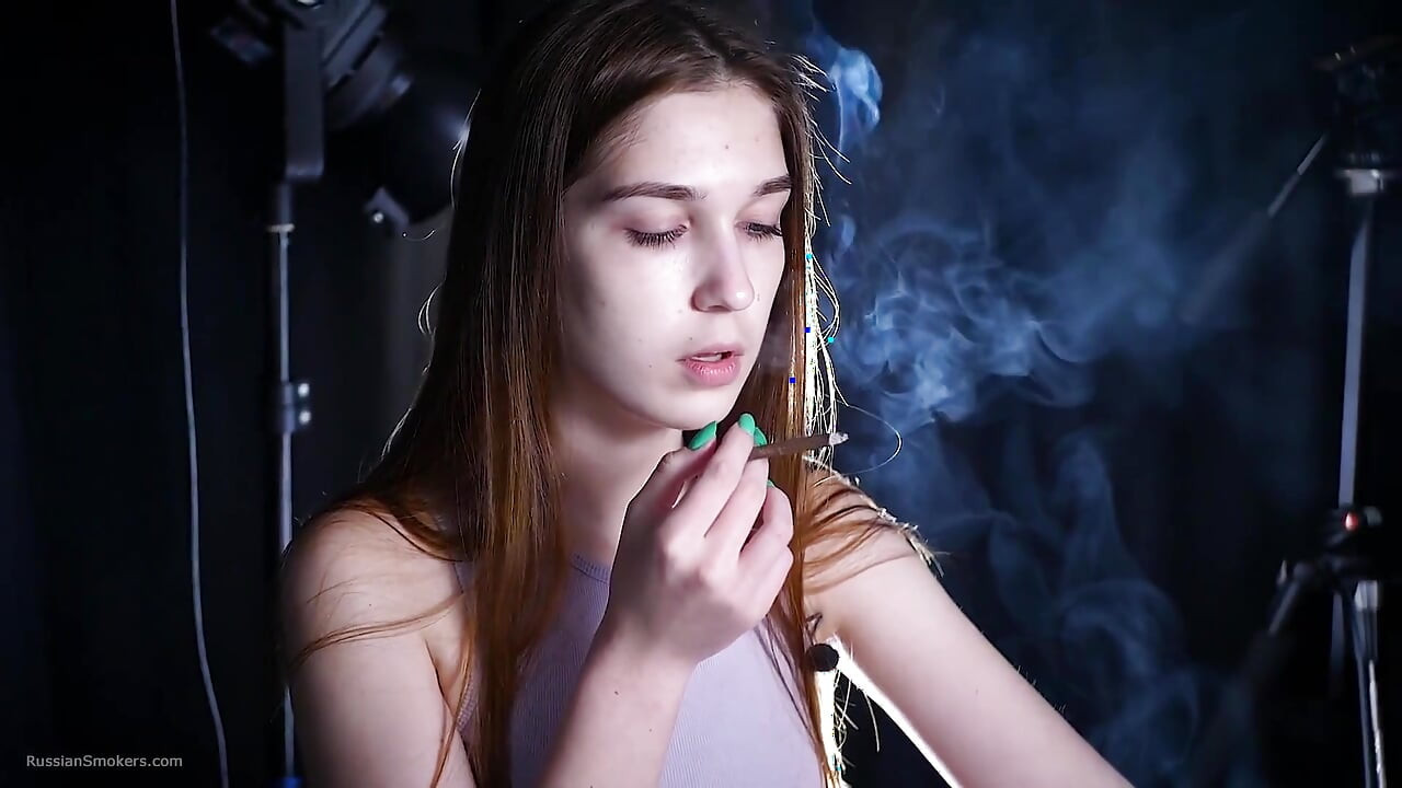 Mlada crvenokosa puši s tirkiznim noktima