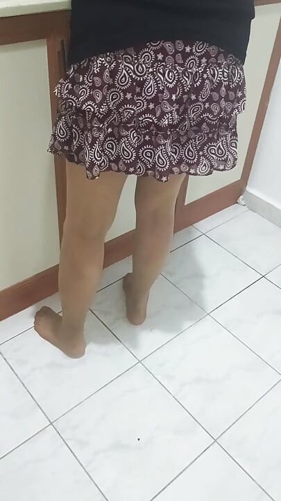 Mature woman in sheer stockings doing housework in the kitchen.
