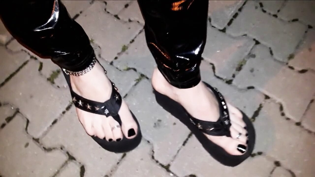 crossdresser on a public street in latex leggings and sexy platform flip flops