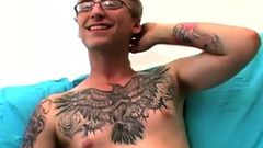 Un geek amateur avec des lunettes et des tatouages ​​caresse sa grosse bite