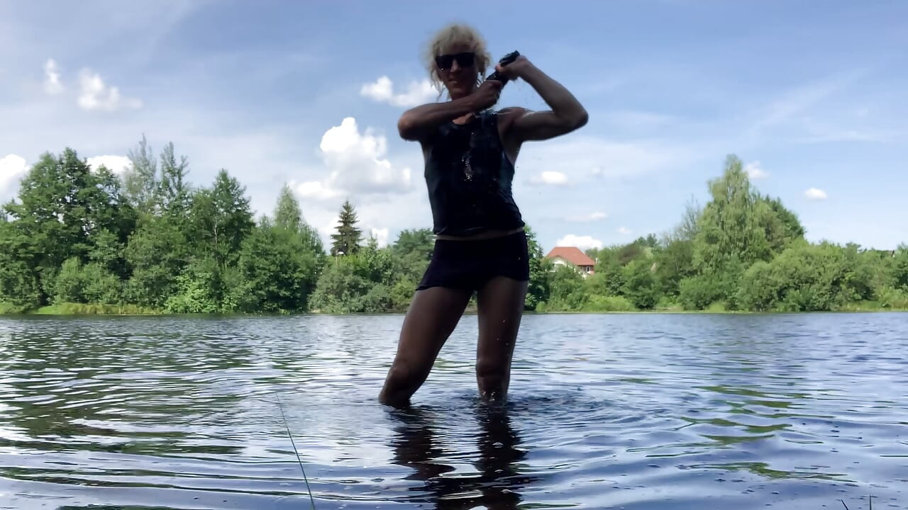 Trans djevojka Alexa Cosmic pliva i igra se u jezeru u crnoj kratkoj i plavoj majici