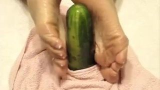 Oiled soles stroking a cucumber