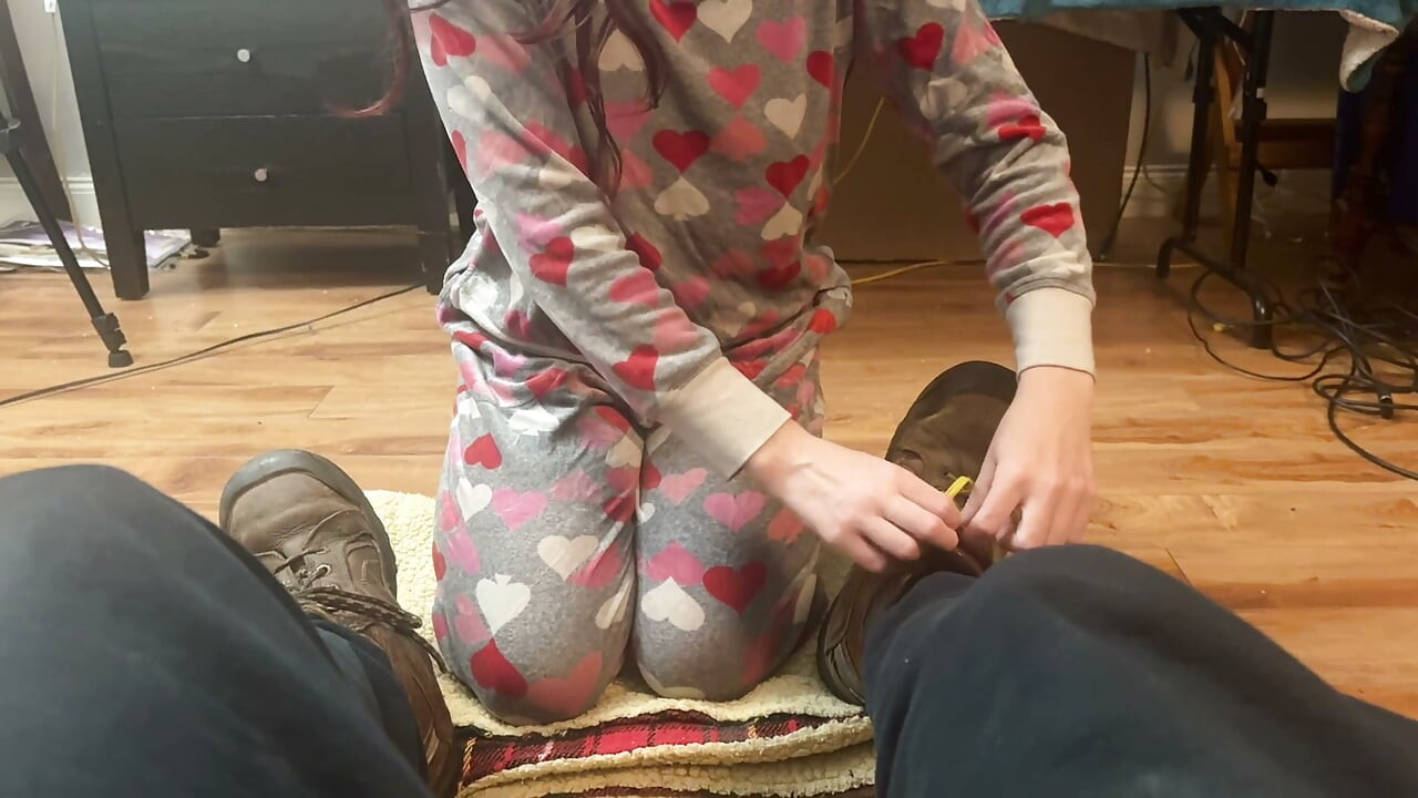 girl takes cares of mans feet after work. she takes off his boots and socks and smells them deeply