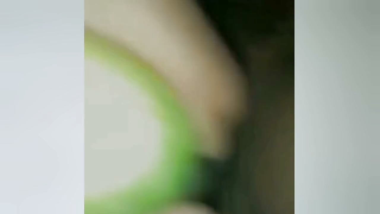 A young woman, suffering from the pain of not having her partner near her, is inserting a cucumber into her pussy.