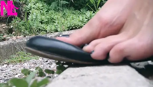 Игра с обувью в черных кожаных балетках босиком на улице