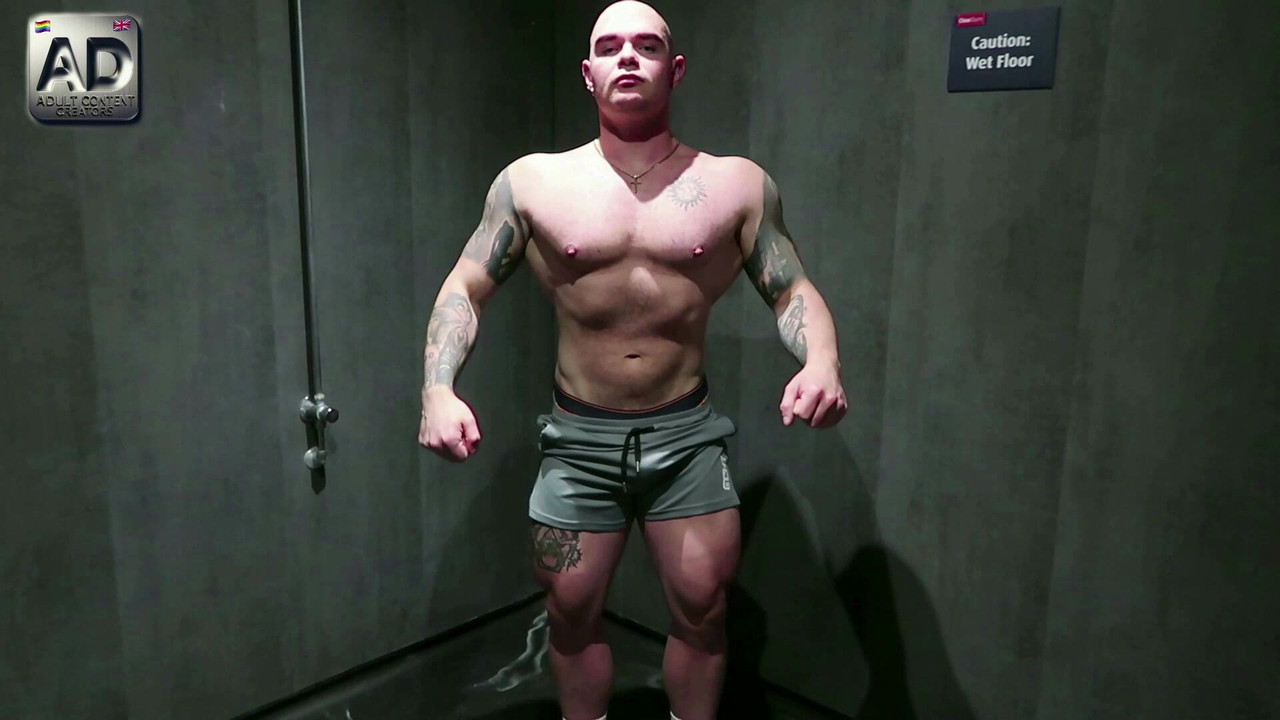 ジムのジョックが筋肉を見せつけ、公衆トイレのクルージングでカットされていない大きなチンポで遊ぶ