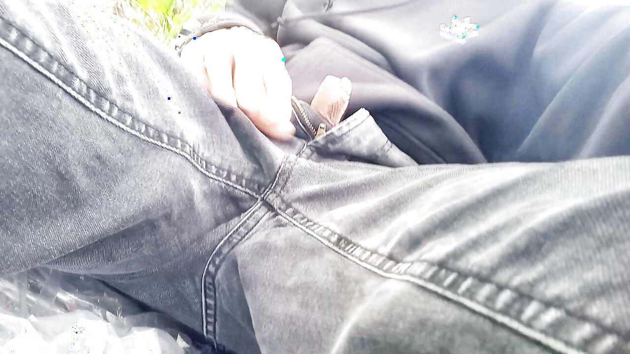 The cute gay twink jerking off his cock, pulled through his fly while outdoors, is Jon Arteen