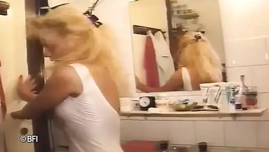 Blonde pissing on her friend in the bathroom