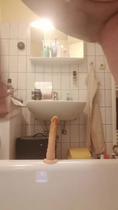 Tranny jerks off with a dildo in her ass in the bathtub