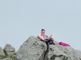 Zoey masturbándose en público en lo alto de una roca en el puerto