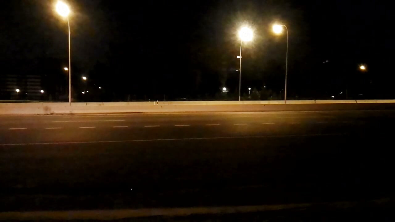 Desnudo en la carretera en frente del tráfico por la noche