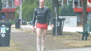 Crossdresser de minifalda de charol, pantalón de plástico en público