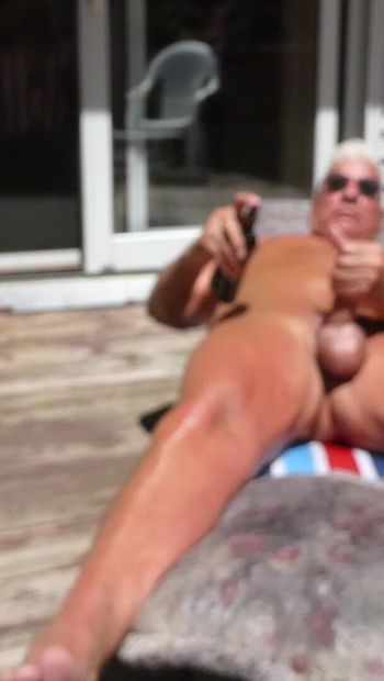 Hombre gay desnudo tomando el sol afuera.