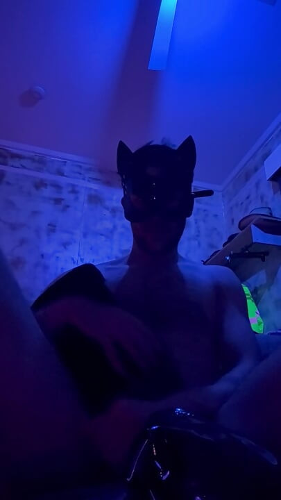 Putting leather boots on in a leather mask