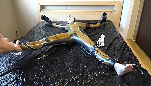 Lateks Danielle yatağa bağlı ve masaj vibratörüyle mastürbasyon yapıyor