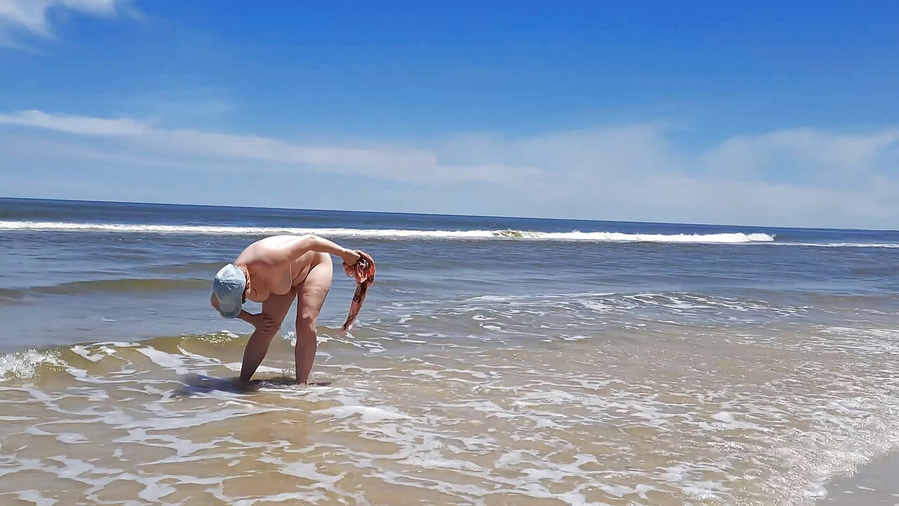 Filmación amateur. Un nudista juega con olas en la orilla del océano.