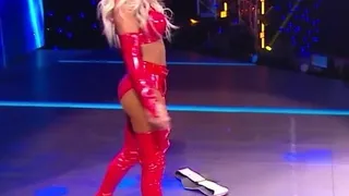 WWE - Carmella в красном наряде стоит над Sasha Banks